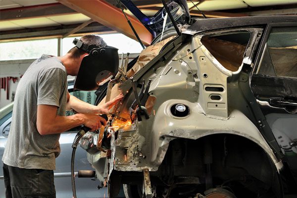 Auto body mechanic at Larry's Body Shop working on a car
